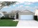 Tan house with a white garage door and well-manicured lawn at 1897 Caryle Ln, The Villages, FL 32162