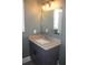 Single vanity in a modern bathroom featuring a gray painted cabinet, stone top, and a large mirror at 2437 Bay Lake Loop, Groveland, FL 34736