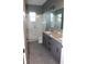 Bright bathroom with a glass walk-in shower, granite countertops, and gray cabinets at 2437 Bay Lake Loop, Groveland, FL 34736