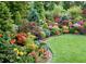 Expansive garden featuring colorful flowerbeds, manicured shrubbery, and a variety of trees at 1001 Michelle Ct, Tavares, FL 32778
