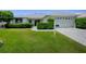 Well-maintained home features a lush front lawn, manicured hedges, and a paver driveway at 1320 Arredondo Dr, The Villages, FL 32162