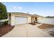 House exterior featuring a white garage door and a walkway at 17159 Se 78Th Crowfield Ave, The Villages, FL 32162