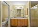 Bathroom with double sinks, wood cabinets, framed mirror, and shower with glass doors at 17848 Se 87Th Bourne Ave, The Villages, FL 32162