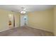 Empty bedroom with a ceiling fan, neutral walls, carpet flooring, with doorways to the en suite bath and laundry room at 17848 Se 87Th Bourne Ave, The Villages, FL 32162