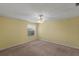 This bedroom features neutral carpet, a ceiling fan, an outside view, and light yellow walls at 17848 Se 87Th Bourne Ave, The Villages, FL 32162