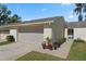 Charming villa featuring a two-car garage and lovely curb appeal with colorful potted plants and well-kept landscaping at 2247 Cypress Cove Dr # E2, Tavares, FL 32778