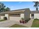 Charming villa featuring a two-car garage and lovely curb appeal with colorful potted plants and well-kept landscaping at 2247 Cypress Cove Dr # E2, Tavares, FL 32778