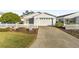 House exterior featuring a white facade, attached garage, and landscaped yard at 2907 Barboza Dr, The Villages, FL 32162