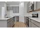 Open kitchen with gray cabinets, stainless steel appliances, subway tile backsplash, and quartz countertops at 2992 Supermarine Rd, Tavares, FL 32778