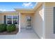 Close-up of the front entrance featuring a screen door, sidelight window, and manicured landscaping at 320 Zingale Ln, The Villages, FL 32163