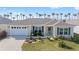 Single-story home featuring a lush green lawn, two-car garage, and tropical palm trees in the distance at 320 Zingale Ln, The Villages, FL 32163