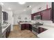 Modern kitchen overlooking the dining and living area with stainless steel appliances, wood cabinets, and light countertops at 320 Zingale Ln, The Villages, FL 32163