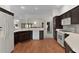 Kitchen featuring wood-look floors, white appliances, and dark wood cabinets at 546 Foxfield Path, The Villages, FL 32162