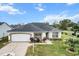 Well-maintained single-story home with mature landscaping, a decorative driveway, and a two-car garage at 603 San Pedro Dr, Lady Lake, FL 32159