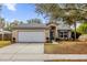 Tan house with white garage door and landscaping, offering curb appeal at 1575 Whooping Dr, Groveland, FL 34736