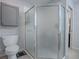 Clean bathroom featuring a frosted glass shower door, a toilet, a wall cabinet, and gray tile flooring at 17242 Se 94Th Coults Cir, The Villages, FL 32162