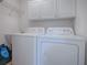 Clean laundry room featuring a white washer and dryer, overhead cabinets, a utility sink, and a wire rack shelf at 17242 Se 94Th Coults Cir, The Villages, FL 32162