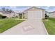 Tan house with a decorative driveway and landscaping at 17466 Se 75Th Coachman Ct, The Villages, FL 32162