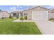 Tan house with a garage and well-manicured lawn at 17466 Se 75Th Coachman Ct, The Villages, FL 32162