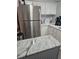 Close up of a stainless steel refrigerator and island in a kitchen with white cabinets at 30 Riverview Dr, Fruitland Park, FL 34731