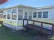 Exterior view featuring a ramp leading to the enclosed porch, offering great accessibility at 975 Cr 461, Lake Panasoffkee, FL 33538