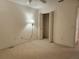 A standard bedroom with neutral colored walls, carpeted floors, bi-fold closet, and a wall lamp at 16914 Se 96Th Chapelwood Cir, The Villages, FL 32162