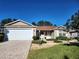 Tan one-story house with a two-car garage and landscaped yard at 16914 Se 96Th Chapelwood Cir, The Villages, FL 32162