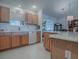 Kitchen with wood cabinets, white appliances, and a kitchen island at 16914 Se 96Th Chapelwood Cir, The Villages, FL 32162