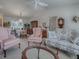 Living room with floral sofas, pink armchairs, and a glass coffee table at 16914 Se 96Th Chapelwood Cir, The Villages, FL 32162