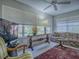 Light-filled living room with a floral sofa, large windows, and a decorative console table at 16914 Se 96Th Chapelwood Cir, The Villages, FL 32162