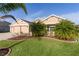 Tan two-story house with palm trees and manicured lawn at 3113 Sweetgum St, The Villages, FL 32163