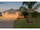 Attractive tan house with three-car garage at dusk at 3113 Sweetgum St, The Villages, FL 32163