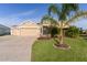 Tan three-car garage home with palm trees and manicured lawn at 3113 Sweetgum St, The Villages, FL 32163