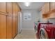 Laundry room with wood cabinets, a sink, and red washer/dryer set at 3113 Sweetgum St, The Villages, FL 32163