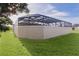 Screened pool enclosure with a large grassy area at 3113 Sweetgum St, The Villages, FL 32163