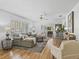 Bright living room with hardwood floors, shutters, light gray sofa, and view to the outside through sliding glass doors at 3213 Archer Ave, The Villages, FL 32162