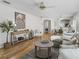 Bright living room with hardwood floors, shutters, view to the dining area and light gray sofa at 3213 Archer Ave, The Villages, FL 32162