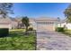 Charming home features a manicured lawn, neat shrubbery, and a brick paved driveway at 1018 Green Gate Blvd, Groveland, FL 34736