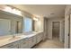 Bathroom with double vanity, white cabinets, large mirror, and a view of a closet and shower at 1710 Summer Rose Dr, Mount Dora, FL 32757