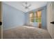 Comfortable bedroom with blue walls, plush carpet, natural light, and a ceiling fan at 1828 Feliciana Ter, The Villages, FL 32162