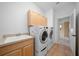 Bright laundry room featuring cabinetry, sink, tile floor, and modern washer/dryer at 1828 Feliciana Ter, The Villages, FL 32162