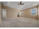 Spacious main bedroom featuring carpet, tray ceiling, large windows, and ceiling fan at 1828 Feliciana Ter, The Villages, FL 32162