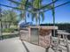 Outdoor kitchen with grill and mini-fridge under a screened enclosure at 1877 Quailey Ct, The Villages, FL 32163