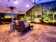 Night view of a relaxing screened patio with wicker furniture at 1877 Quailey Ct, The Villages, FL 32163