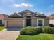 Tan house with a 2-car garage, and well-manicured lawn at 223 Knollwood Dr, Davenport, FL 33837