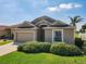 Tan house with a 2-car garage and neatly trimmed shrubs at 223 Knollwood Dr, Davenport, FL 33837