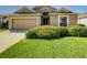 Tan one-story house with a two-car garage and lush landscaping at 223 Knollwood Dr, Davenport, FL 33837