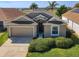 Tan house with a 2-car garage and lush landscaping at 223 Knollwood Dr, Davenport, FL 33837