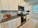 Close up of the kitchen with granite countertops and stainless steel appliances including a microwave and range oven at 2676 Spider Lily Ct, Clermont, FL 34711