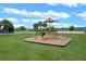 Community playground with green grass and a variety of play equipment overlooking a scenic lake at 2676 Spider Lily Ct, Clermont, FL 34711